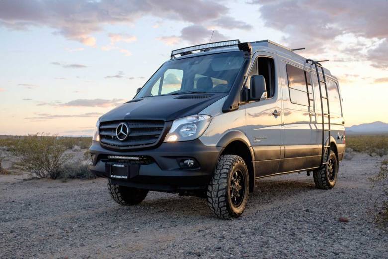 A custom Sportsmobile Sprinter 4x4 camper conversion featuring an LED light bar, side ladder, and equipped with larger wheels and tires.