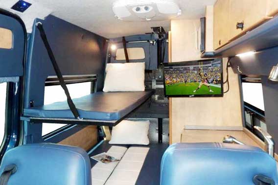 Van conversion with built in TV, cabinets, and double beds.