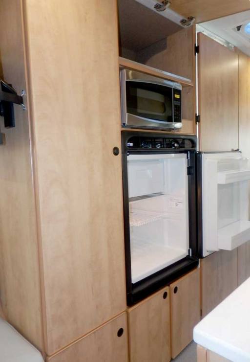 Ford Transit camper conversion featuring a microwave and refrigerator in the galley.