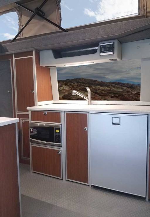 Porta Pottie stows under microwave inside a custom Sportsmobile Sprinter RB 150M conversion van.