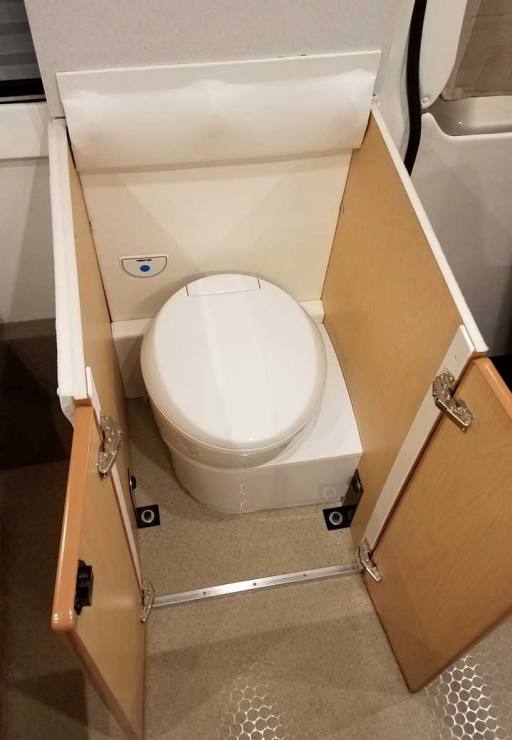 Interior view of a custom Sportsmobile Transit conversion van with small cassette toilet that can be easily accessible.