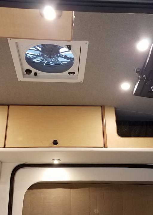 Interior view of a custom Sportsmobile Transit conversion van with air conditioner and attic fan.