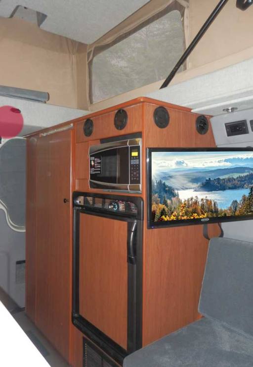 Interior view of a custom Sportsmobile Sprinter van conversion featuring a refrigerator.