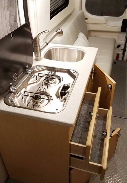 Counter space with a cooktop inside this custom conversion van.