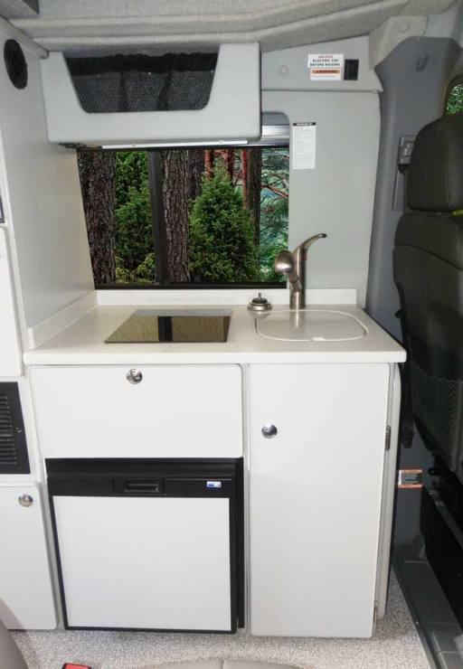 Custom Mercedes-Benz conversion van's galley includes cabinets and appliances.