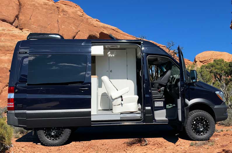 Dark blue Mercedes-Benz Sprinter conversion van with side door open.